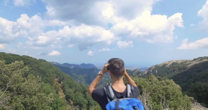Ragazzo esploratore sta guardando le montagne con il binocolo
