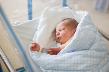 Newborn baby laying in crib in prenatal hospital