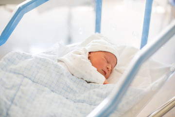 Newborn baby laying in crib in prenatal hospital - obrazy, fototapety, plakaty