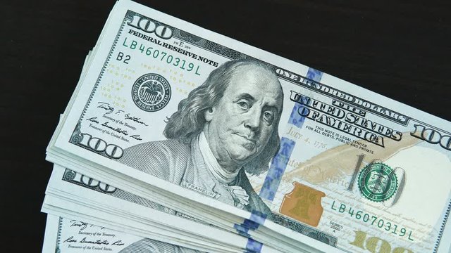 Close-up of a one dollar bills fall on a black table. Business stock footage shot. 
