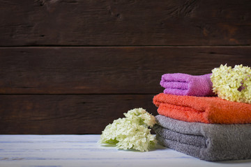 Image of beautiful bath towels of different colors on a wooden background.