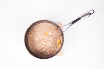 Fototapeta na wymiar Porridge with apple and walnuts in a pot - steaming hot
