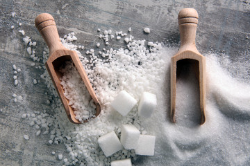 Bowl with white sand and lump sugar on grey background