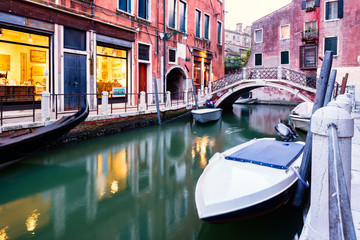 Fototapeta na wymiar Boats and old houses on a narrow canal in Venice at sunset