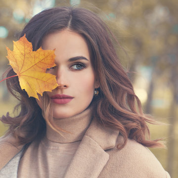 Autumn Beauty. Perfect Woman Fashion Model with Fall Mapple Leaf Outdoors