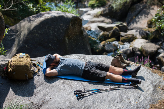 tourist with a backpack resting lying on a rock