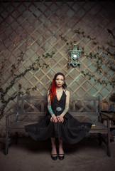 tattooed girl in a black dress, with orange dreadlocks. Girl reading a book, dreaming. The scenery in the Studio: the clock on the wall, old bench. The conceptual idea