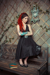 tattooed girl in a black dress, with orange dreadlocks. Girl reading a book, dreaming. The scenery in the Studio: the clock on the wall, old bench. The conceptual idea