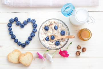Fototapeta na wymiar Romantic breakfast of oatmeal, blueberries, honey, milk and biscuits