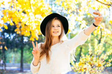 Young happy teenage girls making selfie and having fun in autumn park