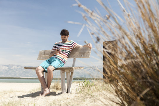 Young man using handy on beach
