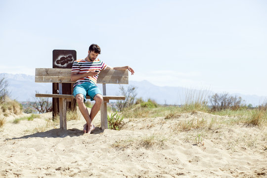 Young man using handy on beach