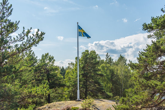 Den Svenska flaggan vajar p&aring; en flaggst&aring;ng i skogsomr&aring;de p&aring; V&auml;rmd&ouml;