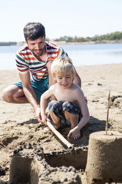 Father and son on beach making sandcastle