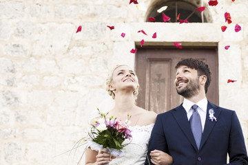 Bride and groom looking at falling rose petals