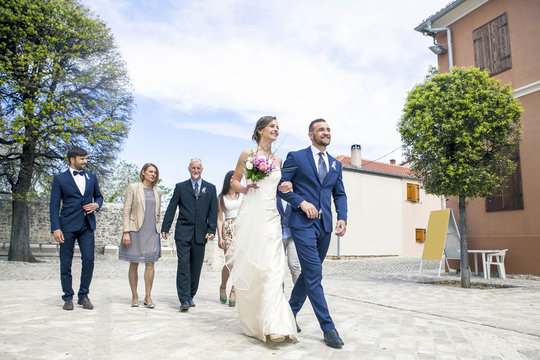 Bride and groom walking with family in background