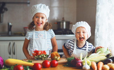 Healthy eating. Happy children prepares  vegetable salad in kitchen