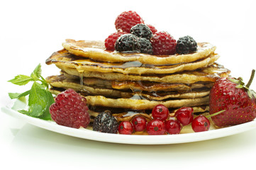 Delicious pancakes with berries and maple syrup on a white background
