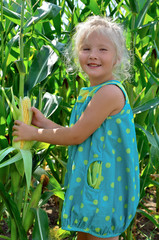 A small, cheerful girl among high, green corn.