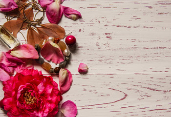 Wooden background framed with petals and pink accessories