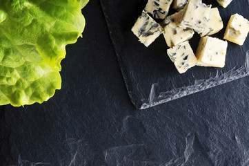 Roquefort slices with a salad leaf on a dark background