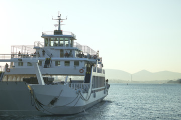 A large white ferry floats away into the distance. Water trail. Greece.