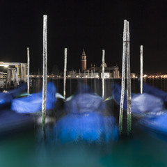 Gondolas moored by St. Mark's Square with the church of San Giorgio di Maggiore in Venice, night view
