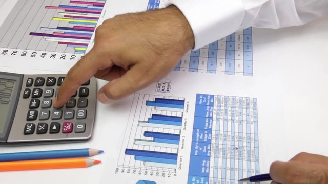 business, people, paperwork, office and technology concept - businessman hands with calculator and pen writing and filing papers on table. Examining business graph and Finance management 