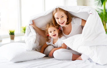  Happy family mother and child daughter laugh in bed