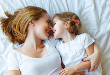 Happy family mother and child daughter laugh in bed