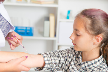 The pediatrician or nurse to vaccinate teen girl, child vaccination.