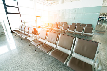 Empty airport terminal waiting area with chairs.