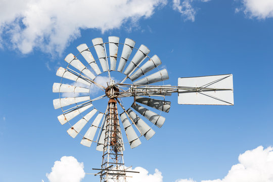 wind-powered water pump against partly cloudy sky