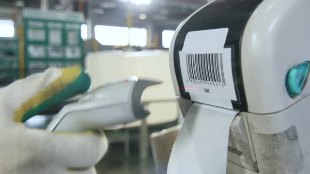 Closeup Worker Hand Scans Barcode Sticker on Printer in Workshop