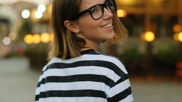 Close up shot of attractive woman in the glasses turning at the camera and smiling on the cafe background. Rear shot