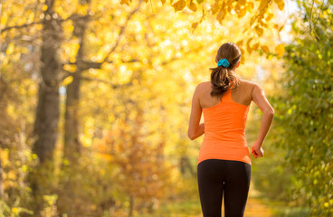 Young brunette woman running in autumn forest