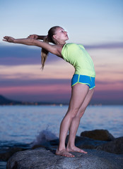 Fototapeta na wymiar Positive female exercising yoga poses at seaside