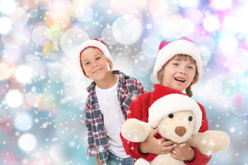 Cute little children in Santa hats on blurred lights background