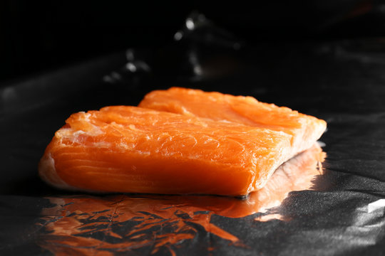 Baking sheet with foil and piece of salmon in oven