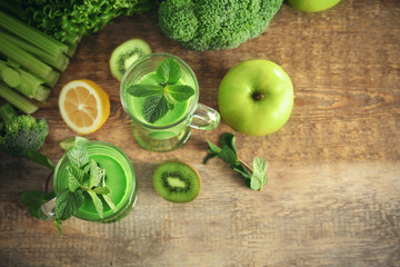Glasses of green healthy juice with vegetables and fruits on wooden table