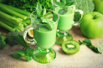 Glasses of green healthy juice with vegetables and fruits on wooden table