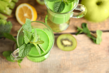 Glass of green healthy juice with fruits on wooden table