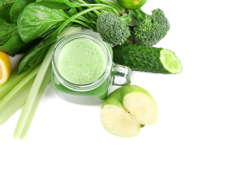Mason jar of green healthy juice with ingredients on white background