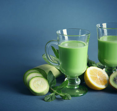 Glass of green healthy juice with ingredients on color background