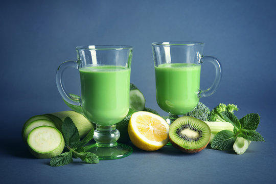 Glasses of green healthy juice with vegetables and fruits on color background