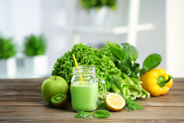 Mason jar of green healthy juice with vegetables and fruits on wooden table