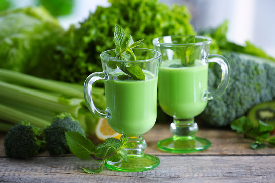 Glasses of green healthy juice with vegetables and fruits on wooden table