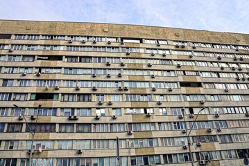 фасад  дома с квартирами и окнами серо коричневого цвета на фоне неба