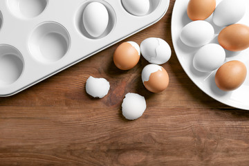 Muffin tin and plate with hard boiled eggs on wooden table