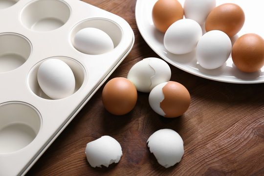 Muffin tin and plate with hard boiled eggs on wooden table